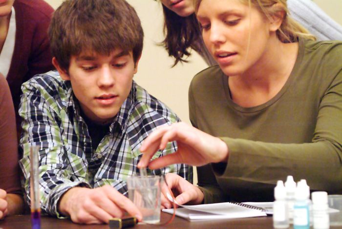 A teacher helping a student through a lab procedure