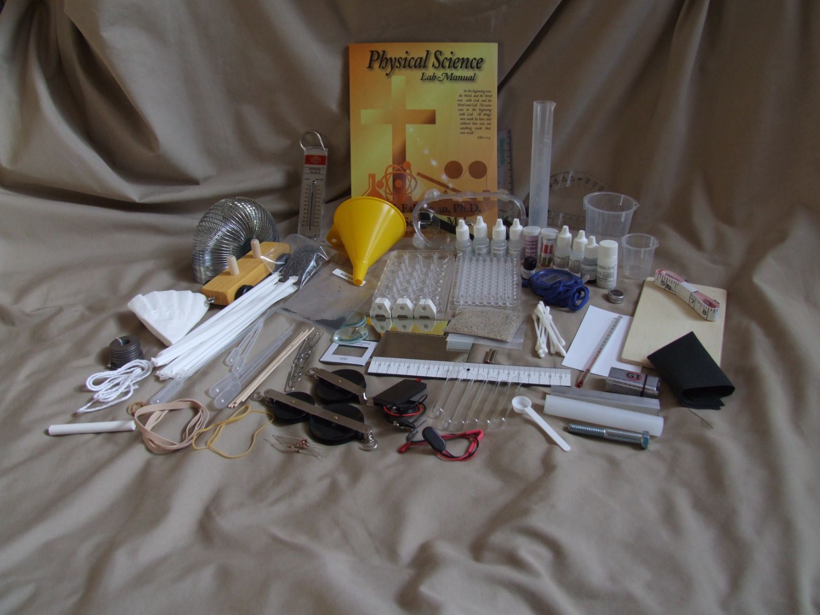 Every item in the Physical Science Kit laid out: manual, spring scale, pulleys, wells and reagents
